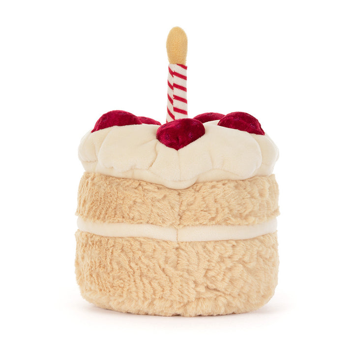 A plush toy shaped like a birthday cake, featuring textured beige layers, white frosting 