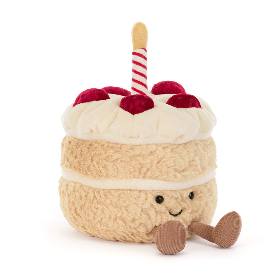 plush toy shaped like a small cake with cream-colored frosting, red cherries on top, a red-and-white striped candle 