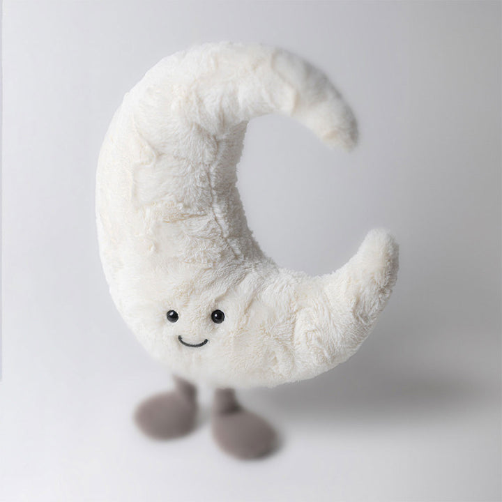 Plush toy shaped like a crescent moon with a smiling face on a white background
