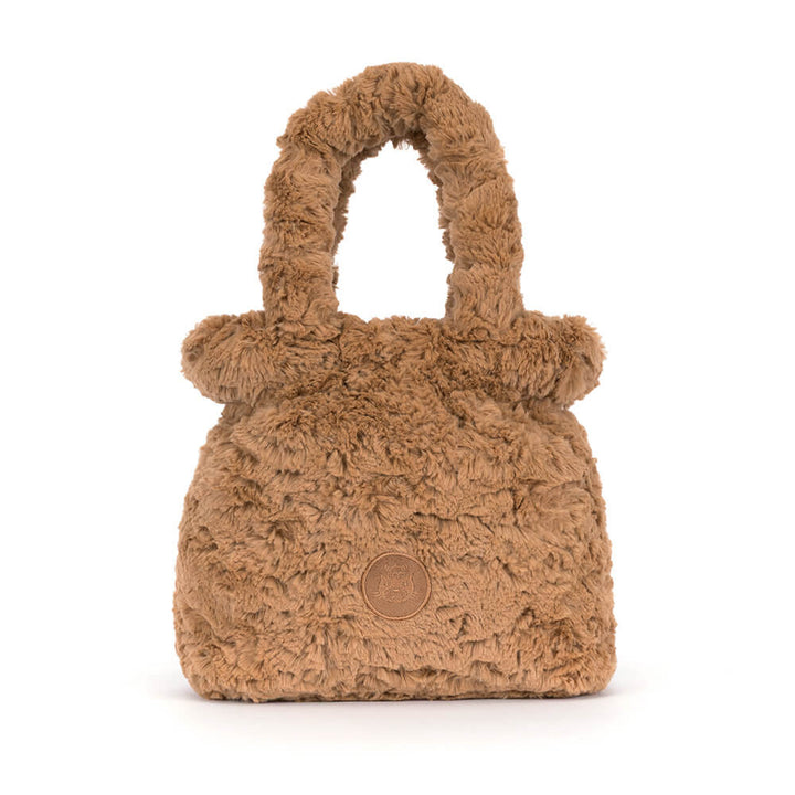 A small brown faux fur handbag with a top handle and a circular embossed logo patch