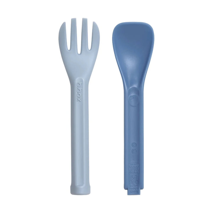 b.box Lunch Cutlery Fork + Spoon Duo 2-pack in Horizon, displayed on a lunch mat with food items.
