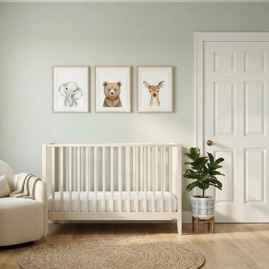 Dadada Furniture Lala 3 in 1 Convertible Crib Cribs & Toddler Beds Almond Milk -  Nursery room with a crib, decorative plants, and framed animal prints on the wall.