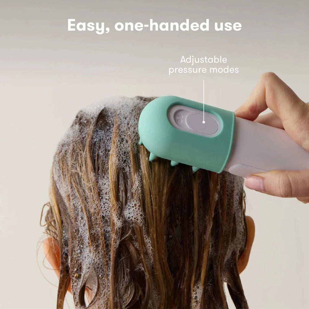 Fridababy - Control the Flow Bath Sprayer  Person using a green and white hair scrubber on their scalp 