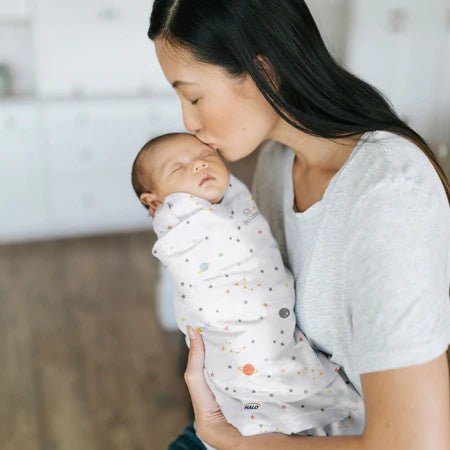 Parent holding baby wrapped in HALO cotton SleepSack Swaddle