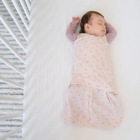 HALO Swaddle 100% Cotton TOG 1.5 SleepSack Swaddle Small with baby wrapped in pink swaddle resting in a white crib