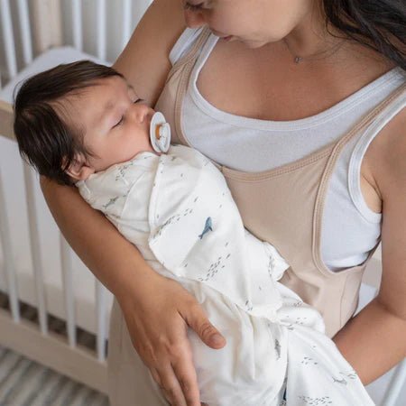 Parent holding baby wrapped in HALO cotton SleepSack Swaddle with blue print