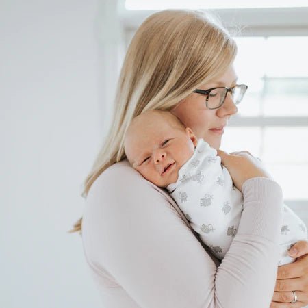Mother holding newborn wrapped in HALO cotton SleepSack Swaddle