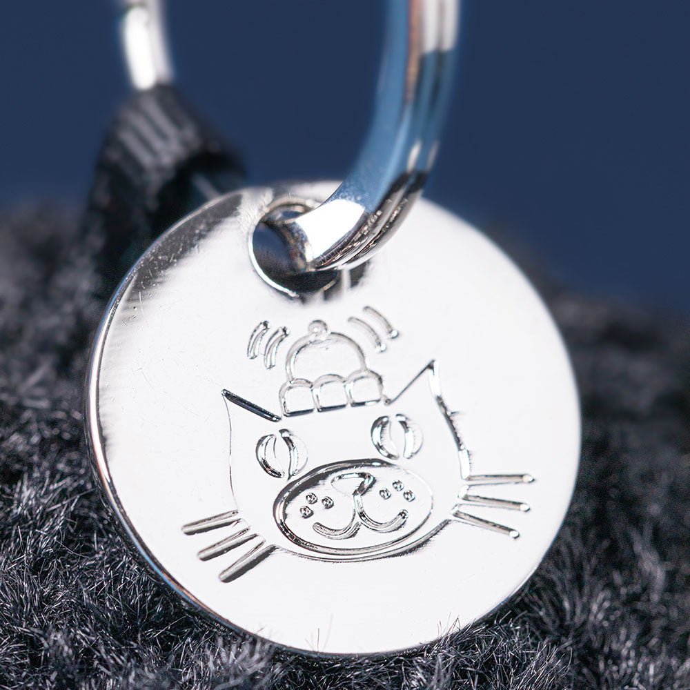 Amuseables Black Hole Bag Charm - Silver cat-shaped pendant on a dark fabric background