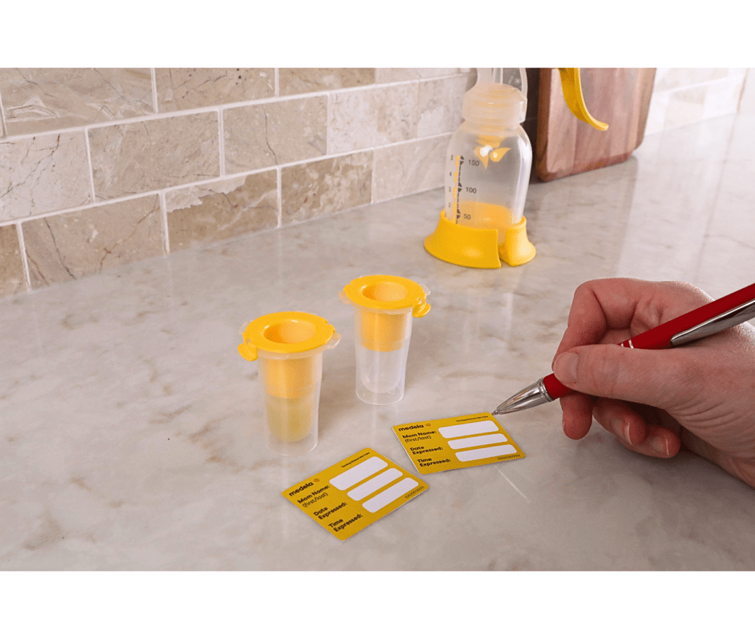 Harmony® with Colostrum Collection and Feeding Kit Breast Pump Yellow and clear plastic containers with labels on a tiled floor.
