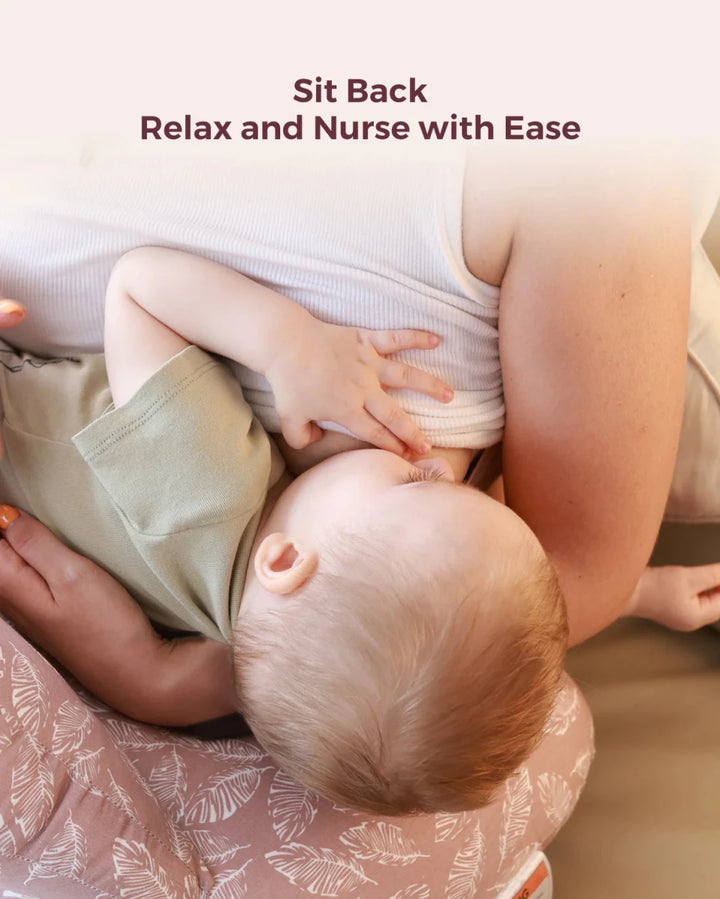 Mother breastfeeding comfortably with the Momcozy Adjustable Nursing Pillow in Pink Leaves for better positioning.