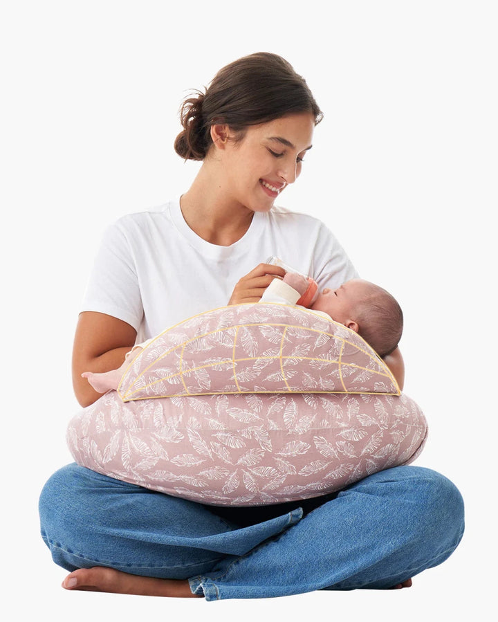 Parent holding a baby with the Momcozy Adjustable Nursing Pillow in Pink Leaves for comfortable breastfeeding support.