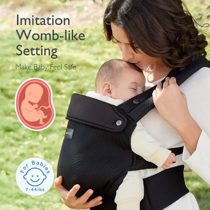Woman holding a baby in a black baby carrier with text about an 'imitation womb-like setting'.