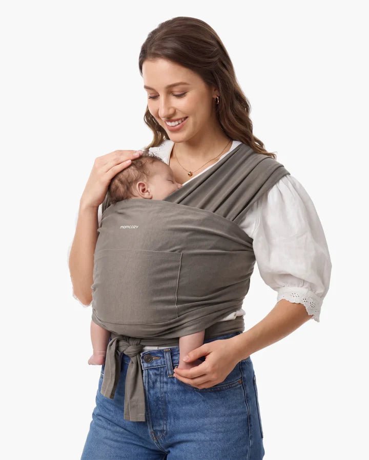 Parent carrying a baby using the Momcozy Easy to Wear Hands-Free Baby Wrap Carrier in Deep Grey color.