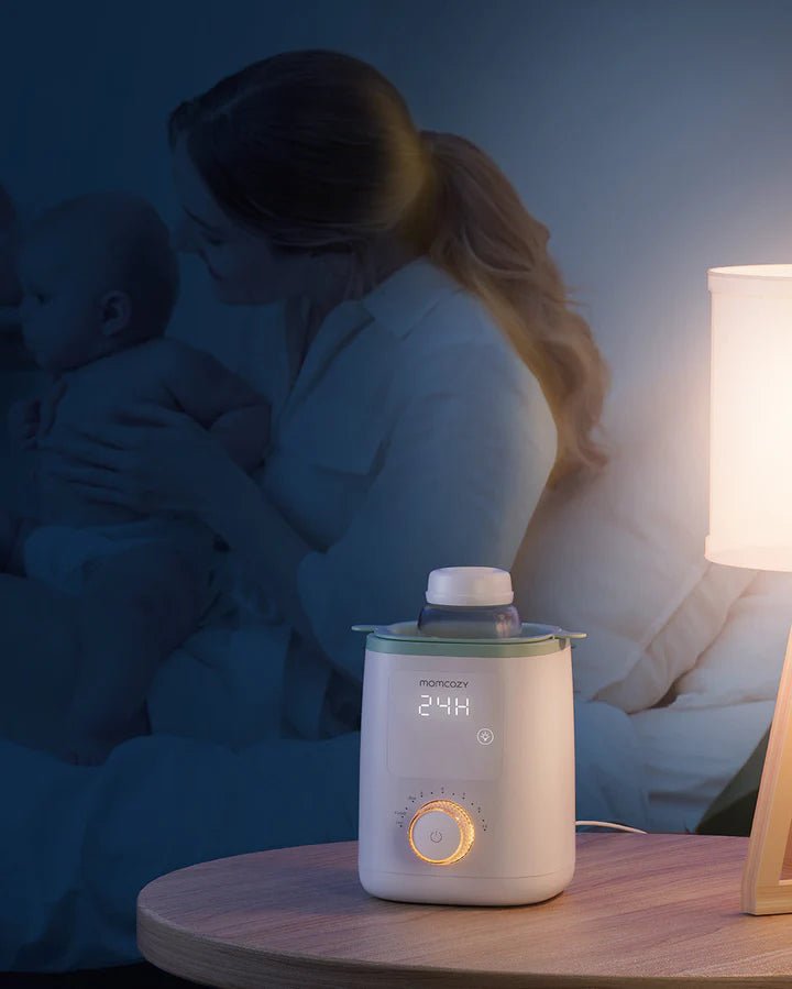 Momcozy Nutri Smart Analog Baby Bottle Warmer beside mother holding baby in bed, ideal for nighttime bottle feeding