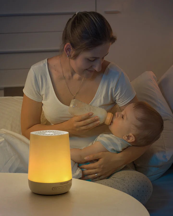 Momcozy Smart Baby Sound Machine providing soft nursery lighting during nighttime bottle feeding and baby care